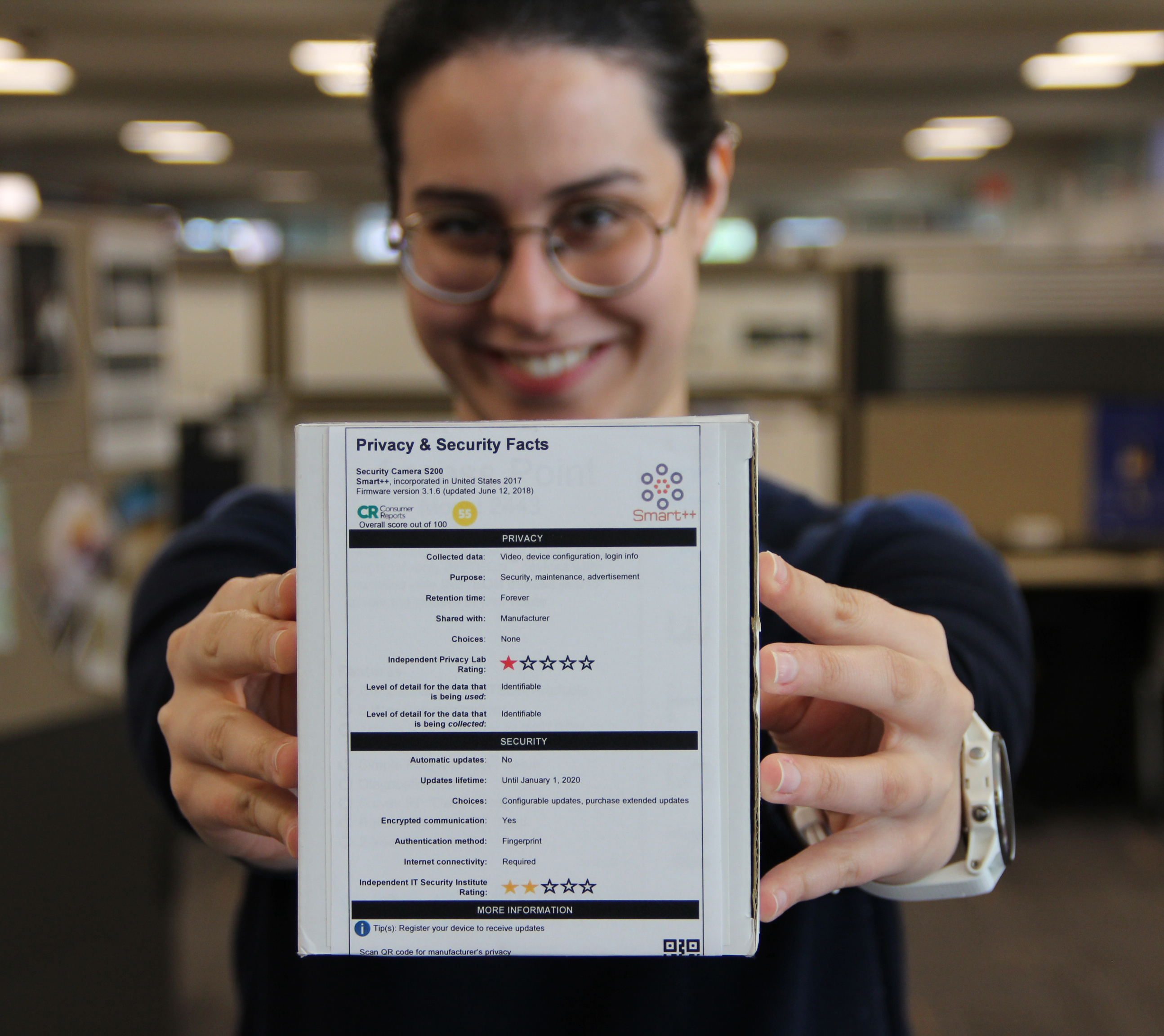 Woman (Pardis) standing with the security label in both hands, thrust out in front of her. The background and woman are mildly out of focus.